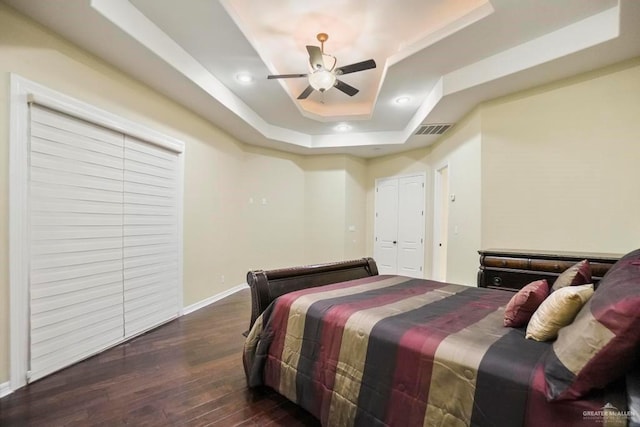 bedroom featuring ceiling fan, dark hardwood / wood-style flooring, and a raised ceiling