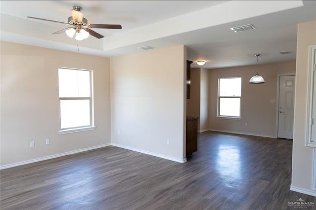 empty room featuring dark wood-type flooring, visible vents, and baseboards