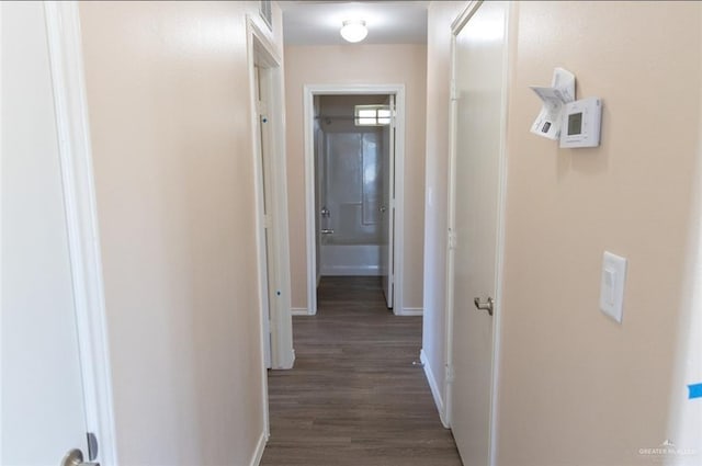 hall with dark wood-style floors, visible vents, and baseboards