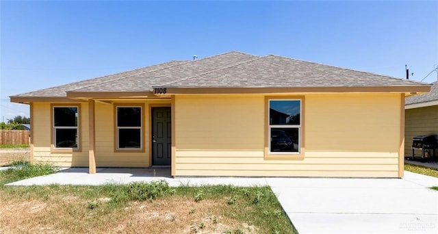 back of property with a patio area, fence, and roof with shingles