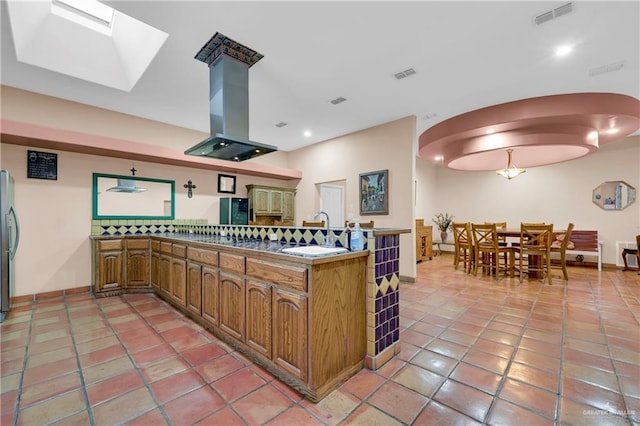 kitchen with light tile patterned flooring, a skylight, sink, island exhaust hood, and kitchen peninsula