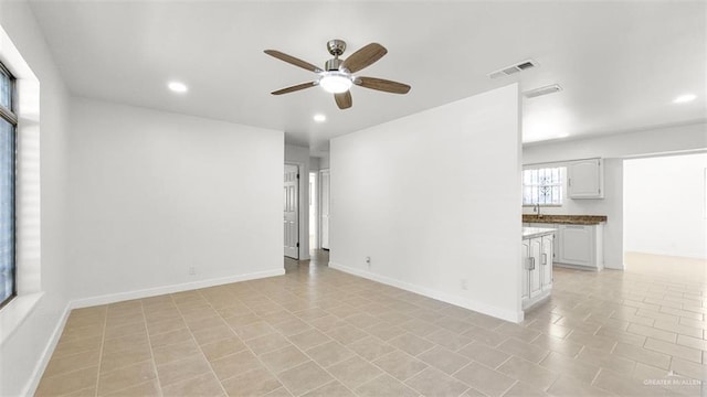 tiled empty room featuring ceiling fan