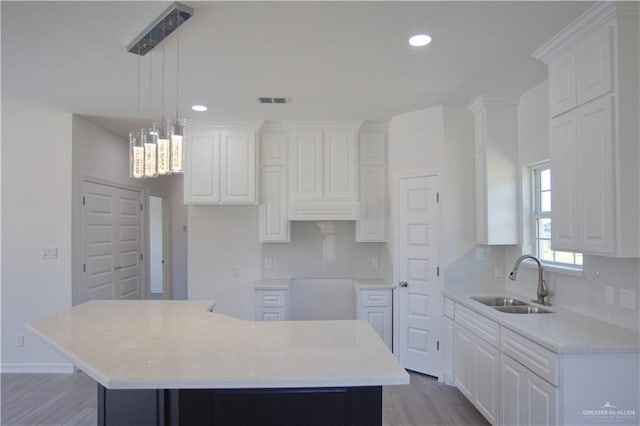 kitchen with a kitchen island, sink, hardwood / wood-style flooring, white cabinetry, and hanging light fixtures