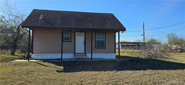 view of front of house with entry steps, a shingled roof, a front yard, and fence