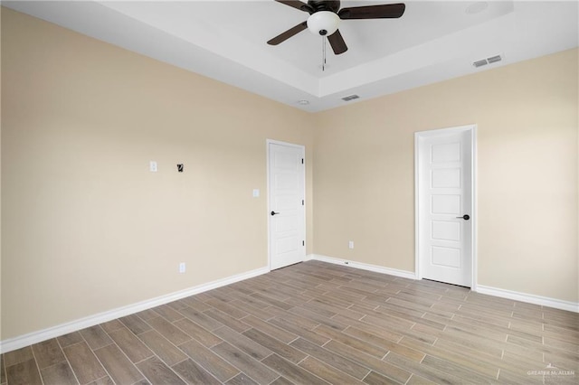 empty room featuring a tray ceiling and ceiling fan