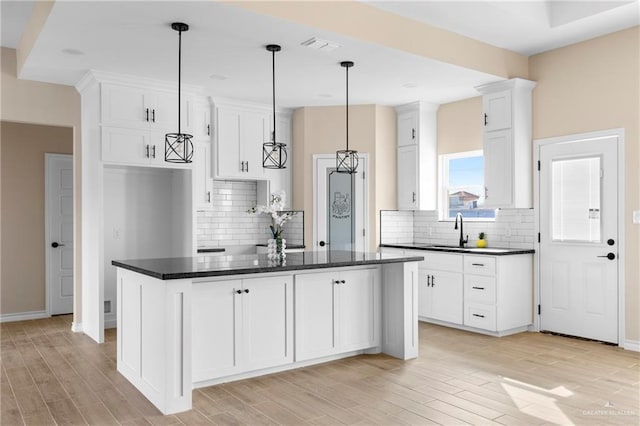 kitchen featuring white cabinets, pendant lighting, a center island, and sink