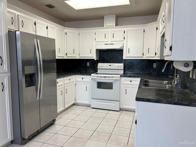 206 Justice Ln, San Juan, TX 78589 - kitchen with stainless steel fridge, white electric stove, under cabinet range hood, light tile patterned floors, and dark countertops