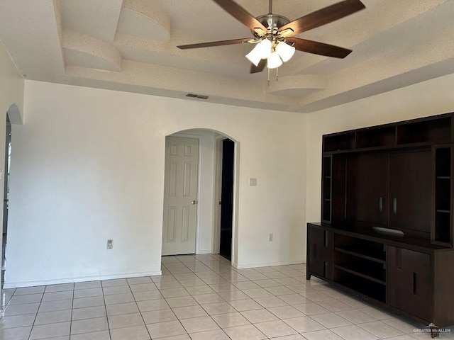 206 Justice Ln, San Juan, TX 78589 - unfurnished living room with arched walkways, a tray ceiling, light tile patterned floors, and ceiling fan