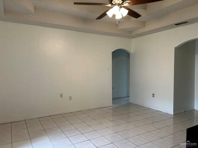 206 Justice Ln, San Juan, TX 78589 - unfurnished room with arched walkways, a ceiling fan, a raised ceiling, and light tile patterned flooring