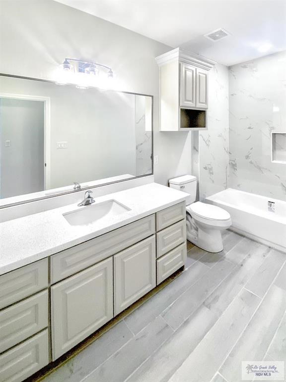 505 Independence Ave, San Benito, TX 78586 - full bathroom featuring vanity, toilet,  shower combination, and visible vents