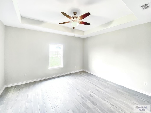 505 Independence Ave, San Benito, TX 78586 - empty room featuring visible vents, light wood-style flooring, a ceiling fan, a tray ceiling, and baseboards
