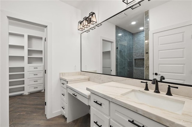 bathroom with a tile shower, vanity, and hardwood / wood-style flooring