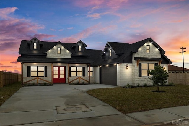 view of front of home featuring a garage, french doors, and a lawn