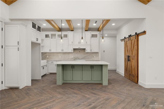 kitchen featuring beam ceiling, hanging light fixtures, a barn door, and dark parquet floors