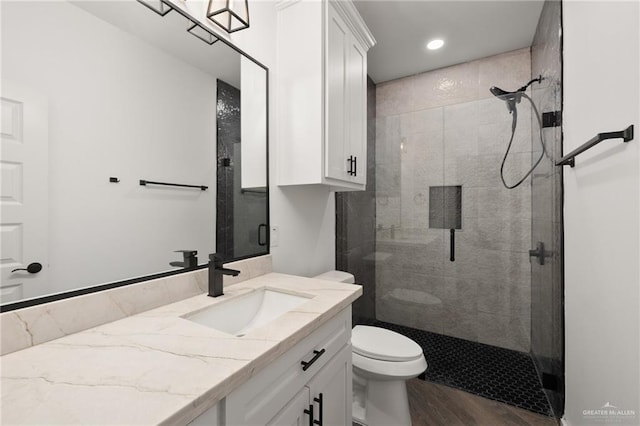 bathroom featuring toilet, walk in shower, wood-type flooring, and vanity