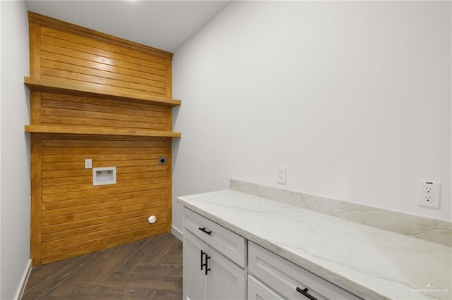 laundry area with dark parquet floors, hookup for a washing machine, and cabinets