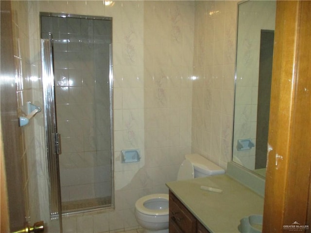 bathroom featuring vanity, a shower with shower door, tile walls, and toilet