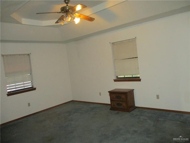 carpeted spare room featuring a tray ceiling and ceiling fan