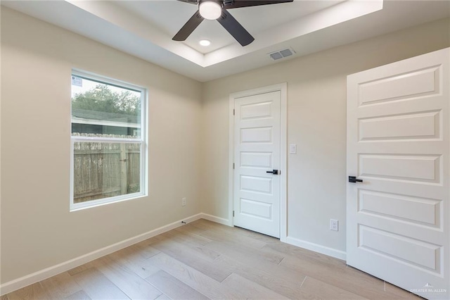 spare room with recessed lighting, a raised ceiling, visible vents, light wood-style floors, and baseboards