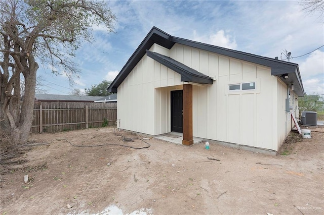 rear view of property featuring board and batten siding, fence, and central air condition unit