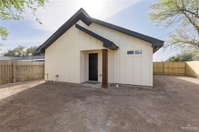 rear view of house with fence and board and batten siding