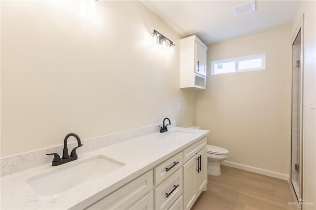 bathroom with toilet, baseboards, a sink, and wood finished floors