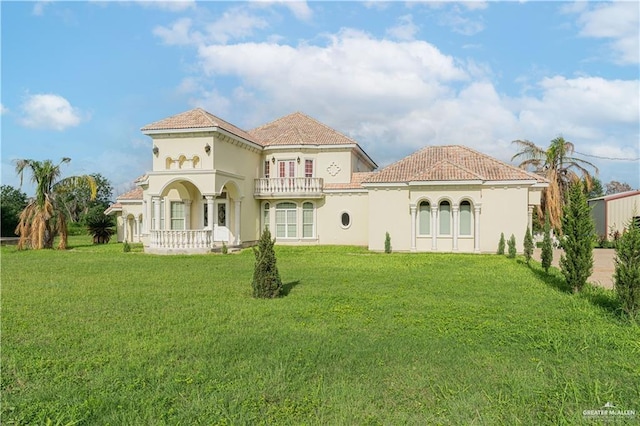 rear view of house featuring a yard, a balcony, and a porch