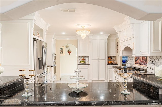 kitchen with white cabinets, stainless steel refrigerator with ice dispenser, and tasteful backsplash