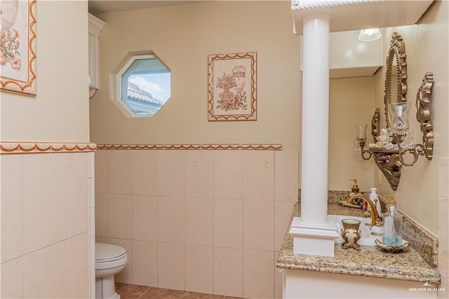 bathroom with decorative columns, vanity, tile walls, tile patterned flooring, and toilet