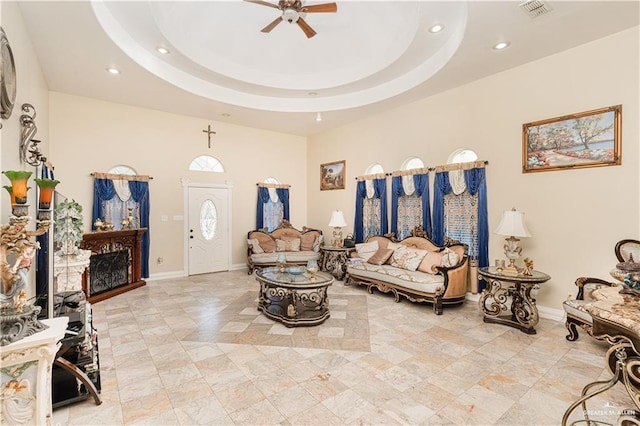 living room with ceiling fan and a tray ceiling