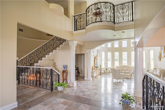 entryway featuring a towering ceiling and ornate columns