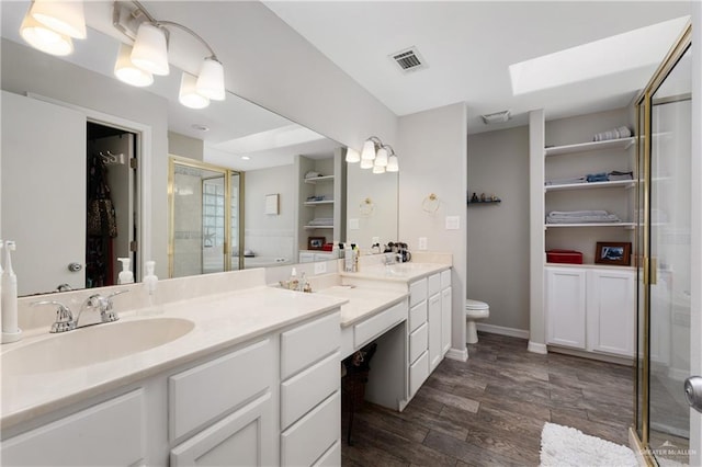 bathroom featuring a skylight, an enclosed shower, vanity, hardwood / wood-style floors, and toilet