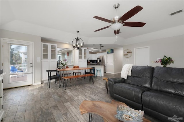 living room with ceiling fan with notable chandelier and wood-type flooring