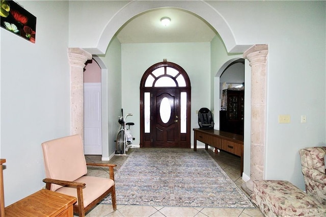 foyer entrance with decorative columns and light tile patterned floors