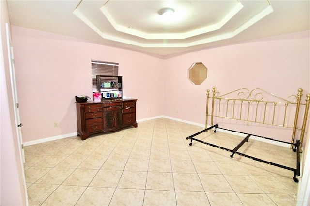 bedroom with light tile patterned flooring and a tray ceiling