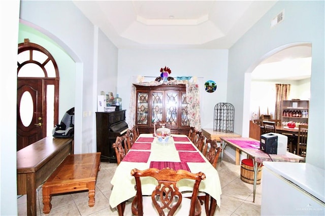 dining room featuring light tile patterned floors and a tray ceiling