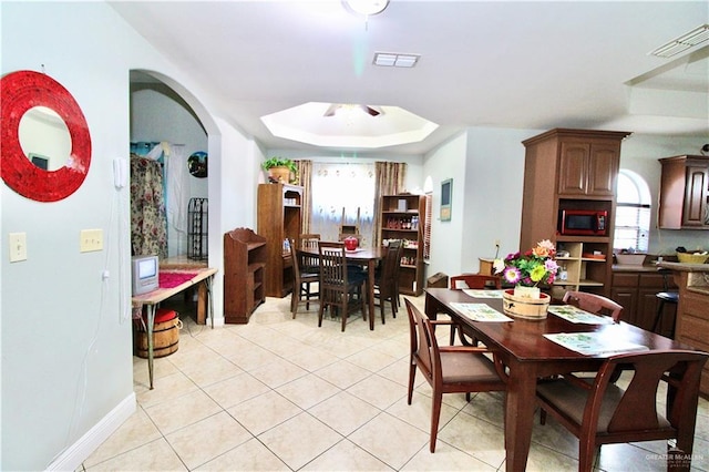 dining area with a raised ceiling and light tile patterned floors