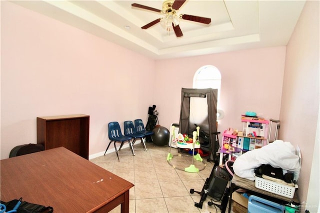 tiled home office featuring a tray ceiling and ceiling fan