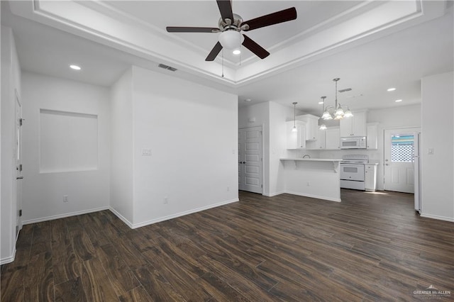 unfurnished living room with a raised ceiling, ceiling fan with notable chandelier, and dark hardwood / wood-style floors