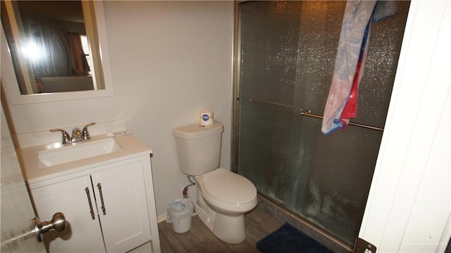 bathroom featuring toilet, hardwood / wood-style flooring, vanity, and a shower with door