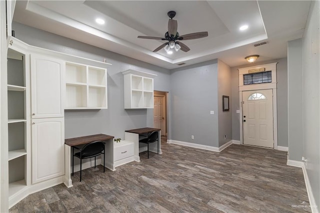 home office with a tray ceiling, dark hardwood / wood-style floors, and ceiling fan