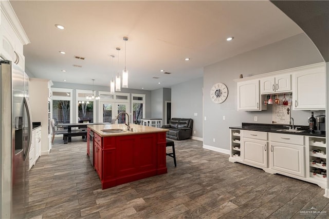 kitchen featuring white cabinetry, sink, pendant lighting, and stainless steel refrigerator with ice dispenser