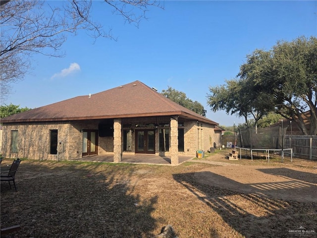 rear view of property featuring a patio area, a trampoline, and french doors