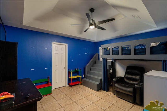 tiled bedroom featuring a tray ceiling and ceiling fan