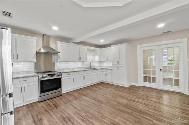 1018 N Keralum Ave, Mission, TX 78572 - kitchen with wall chimney range hood, appliances with stainless steel finishes, a sink, white cabinets, and beam ceiling