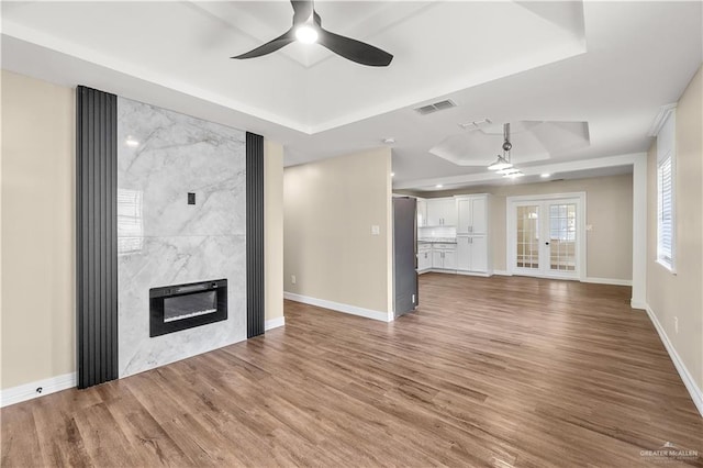 1018 N Keralum Ave, Mission, TX 78572 - unfurnished living room featuring a tray ceiling, a ceiling fan, a fireplace, and wood finished floors