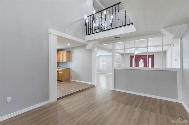 7201 S San Marcos St, Pharr, TX 78577 - unfurnished living room featuring wood finished floors, ceiling fan, baseboards, a towering ceiling, and a chandelier