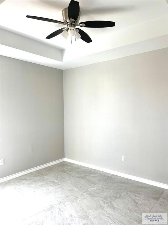 spare room featuring baseboards, a raised ceiling, and a ceiling fan