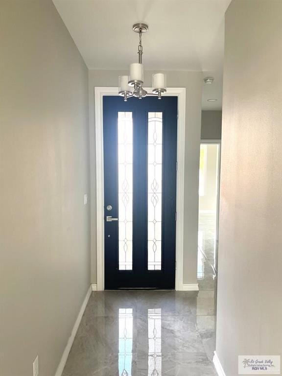 foyer with marble finish floor, an inviting chandelier, and baseboards