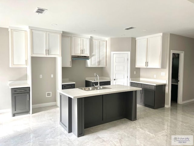 kitchen featuring marble finish floor, an island with sink, a sink, and visible vents